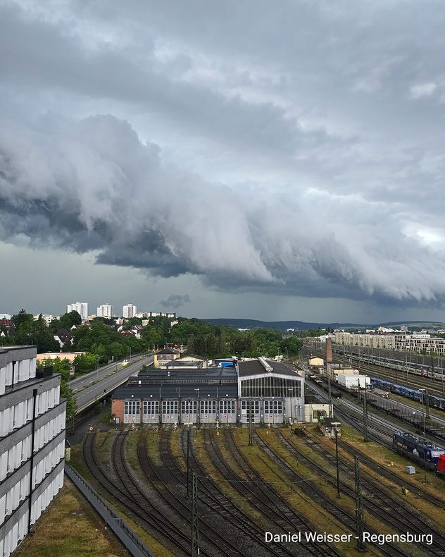 Tiefe, walzenförmige Gewitterwolke über Regensburg. Unter der Wolke sind Bahnanlagen und Gebäude der Stadt zu sehen.