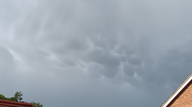 Grey Mammatus clouds pictured above houses.