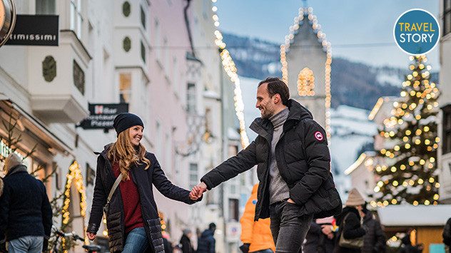 Ein Paar, das sich an den Händen hält, schlendert durch die beleuchtete Altstadt von Sterzing. (c)  TG Sterzing / Wisthaler