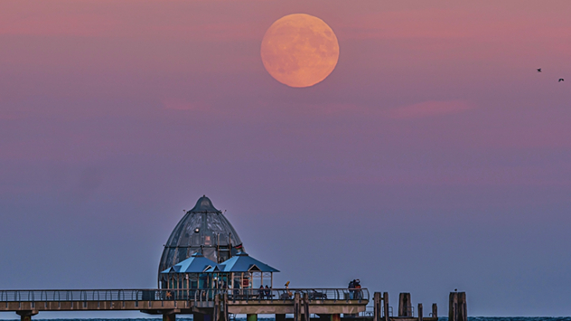 Der Mond geht über dem Ostseebad Grömitz auf.