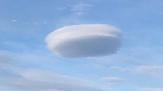 LinsenfÃ¶rmige Wolke (Lenticularis) am Himmel Ã¼ber Ruthin, Nordwales â sie erscheint glatt und elliptisch, fast wie ein UFO, vor blauem Himmel mit vereinzelten Wolken. Typisch fÃ¼r wellenfÃ¶rmige Luftbewegungen in der NÃ¤he von Bergen. (c) Vince Gill