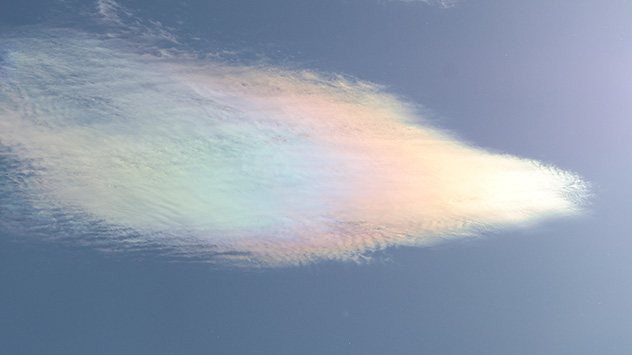 In Perlmuttfarben schimmernde irisierende Wolke vor blauem Himmel.