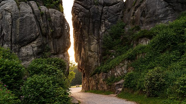 Sonnenuntergang zwischen den Externsteinen im Teutoburger Wald bei Horn-Bad Meinberg, flankiert von steilen Felsw&aumlnden und grüner Vegetation. (c) teddiviscious/Shutterstock.com