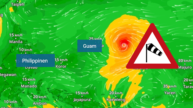 Mapa meteorológico del Pacífico occidental, con Filipinas a la izquierda y Guam en el centro. Al este de Guam gira un ciclón tropical muy marcado con un ojo claramente reconocible. Las zonas de color amarillo a naranja delimitan el campo de la tormenta, mientras que las líneas de corriente blancas muestran el movimiento circular del aire. Sobre ellas aparece un símbolo de advertencia con una manga de viento, que indica la presencia de vientos fuertes o riesgo de tormenta.