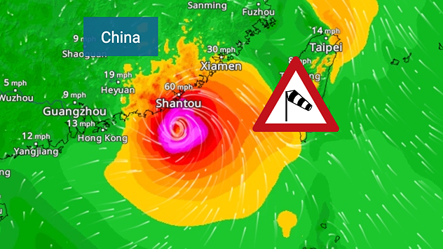 Weather map of the southern Chinese coast and Taiwan showing a powerful tropical cyclone. The eye of the storm is located near the coastal city of Shantou in the Chinese province of Guangdong. Around the centre, intense shades of red, pink and violet indicate gale-force winds, whilst a large orange wind field extends as far as the west coast of Taiwan. An overlaid windsack warning sign indicates dangerous storm winds. Cities such as Hong Kong, Guangzhou, Xiamen, Taipei and Taichung are shown, as are wind speeds and white flow lines illustrating the cyclonic air circulation.