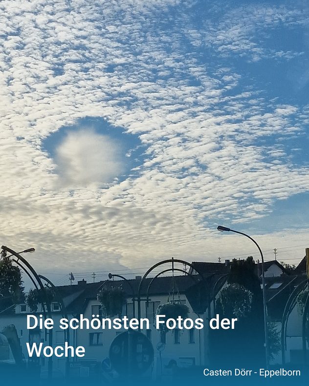 Himmel mit dichter Schäfchenbewölkung und einem runden Wolkenloch über einer Ortschaft mit Häusern und Straßenlaternen.
