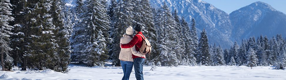Ein Paar, das sich umarmt und auf verschneite Berggipfel blickt. (c) TVB Seefeld