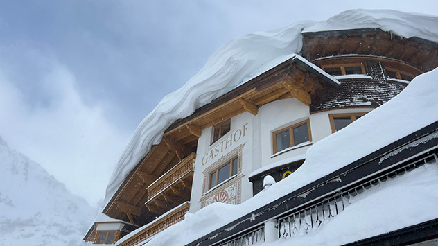 Durch starken bis stürmischen Wind bilden sich an Hausdächern mächtige Schneewechten.