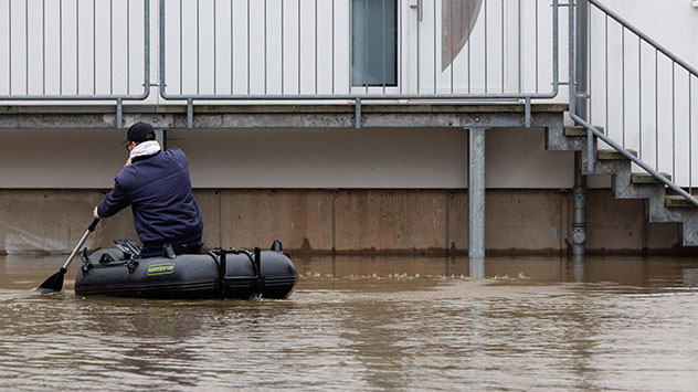 Mann paddelt ein Mann zu seinem Haus, das im Wasser steht.
