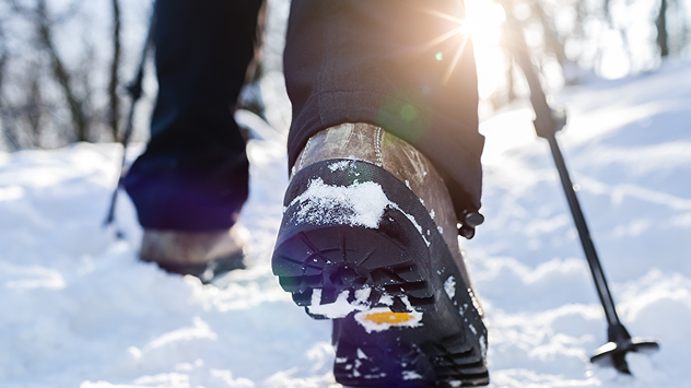 Wanderschuhe und Wanderstöcke im Schnee. 