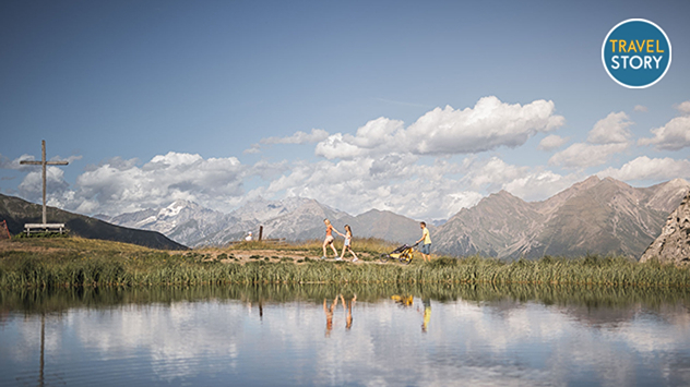 Familienwanderung am See vor Alpenkulisse.