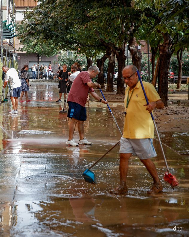 Following the heavy rainfall, local residents are clearing mud and water from a road in the Barcelona area.