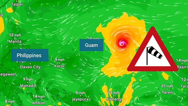 Wind forecast map of the western Pacific showing a powerful typhoon east of Guam with a well-defined eye, strong wind circulation, and a windsock warning icon.