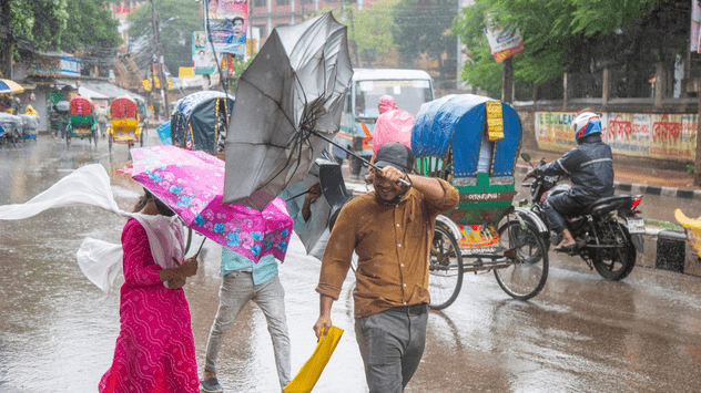 Varias personas se protegen del viento y la lluvia en Dhaka, Bangladesh.