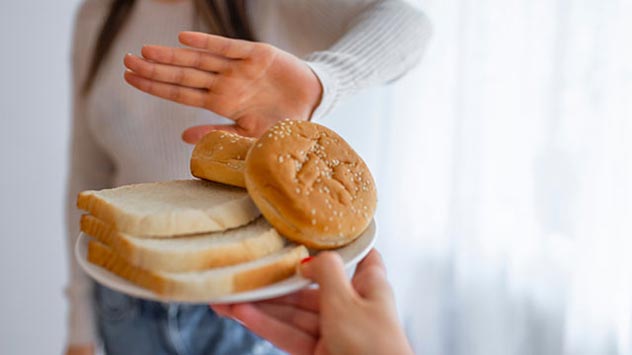 Hand schiebt Teller mit Toast und Weißbrot zurück