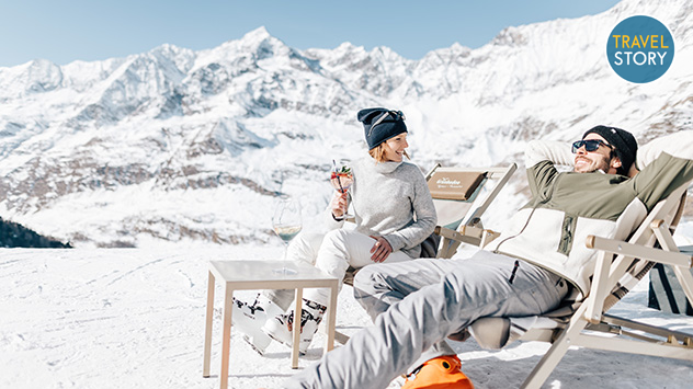 Ein paar genießt die sonnige Winterlandschaft im Liegestuhl.