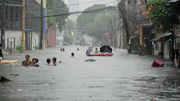 V Quezon City na Filipínach deti plávajú po silných monzúnových dažďoch spôsobených tropickou búrkou WIPHA po zaplavených uliciach.