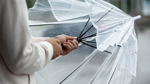 Eine Person spannt einen Regenschirm auf.