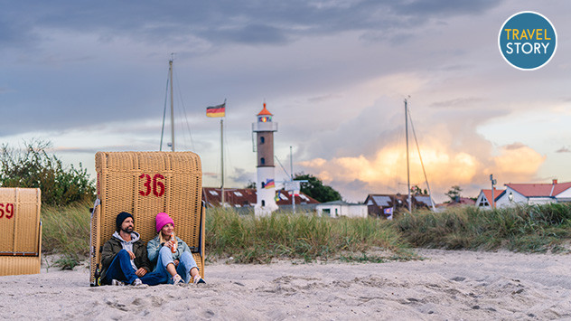 Ein Paar sitzt, an einen Strandkorb gelehnt, am Strand der Ostseeinsel Poel.