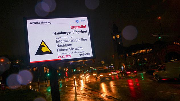 Eine Warntafel an den Landungsbrücken im Hamburger Hafen weist auf die Sturmflut hin