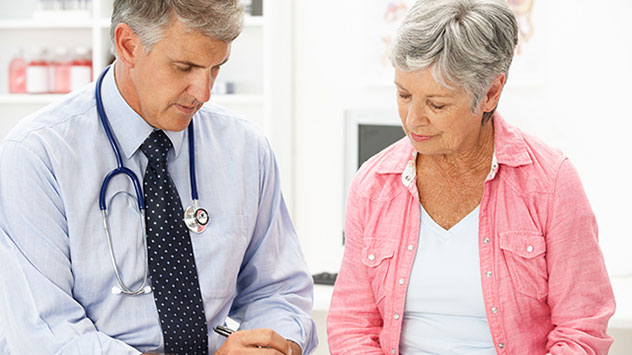 Ältere Dame spricht mit Arzt in Praxis