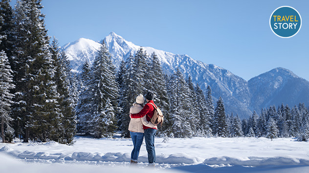 © TVB Seefeld Ein Paar, das sich umarmt und auf verschneite Berggipfel blickt.