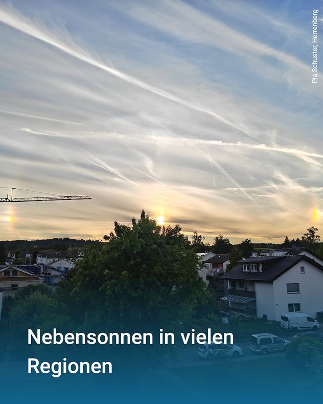 Abendhimmel mit Schleierwolken und sichtbaren Nebensonnen über einer Wohnsiedlung.