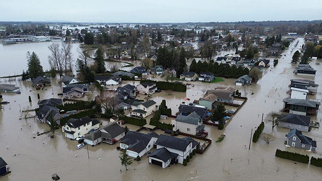 Flooded residential area from the air, houses surrounded by water. Extensive flood damage visible.