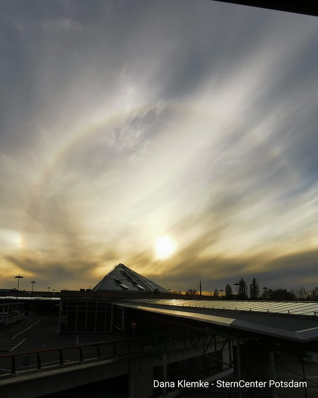 Heller Sonnenhalo mit Schleierwolken über Gebäuden des SternCenters bei Sonnenuntergang.