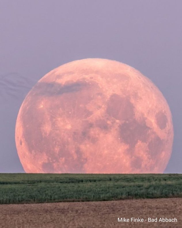 Großer rötlicher Vollmond hinter Feldern bei Bad Abbach kurz nach Mondaufgang.