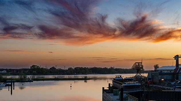 Hafenanlage an der Elbe bei Sonnenuntergang mit farbigen Wolken und Spiegelungen im ruhigen Wasser.