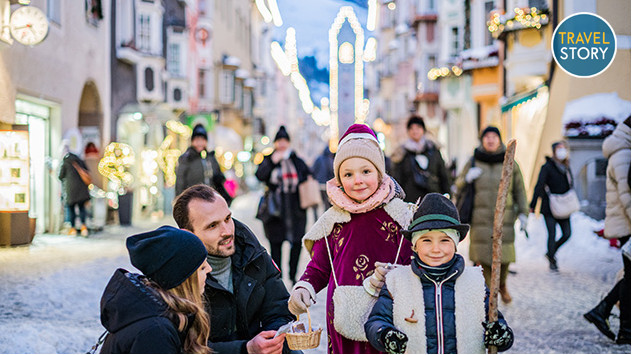 Eine Familie mit zwei Kindern in der verschneiten Altstadt von Sterzing. 