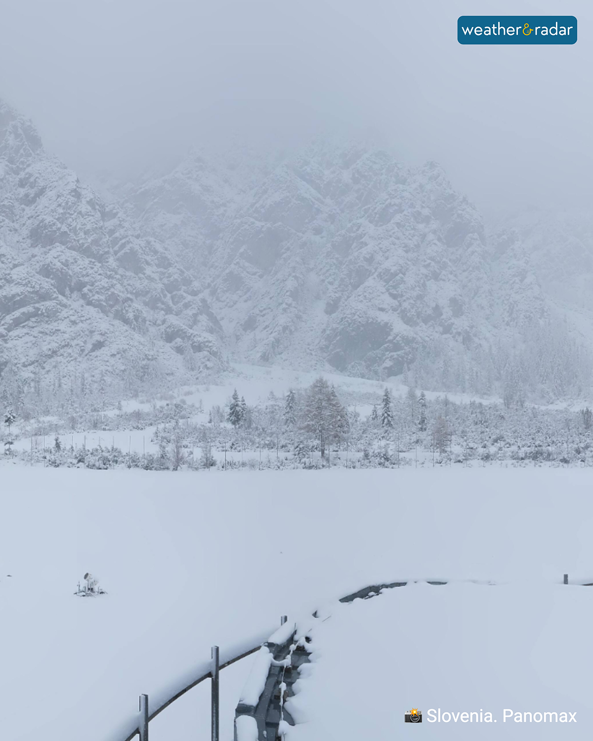 Snow-covered mountain landscape in Slovenia with fog and a peaceful winter atmosphere.