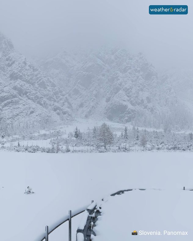 Snow-covered mountain landscape in Slovenia with fog and a peaceful winter atmosphere.