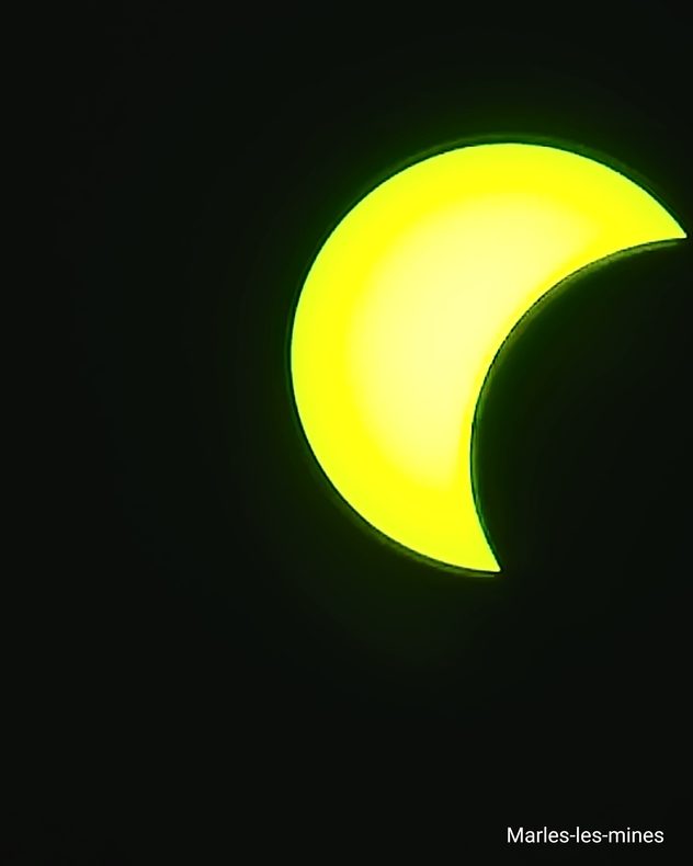 Partielle Sonnenfinsternis über Marles-les-Mines in Frankreich. Der Mond verdeckt einen großen Teil der gelb leuchtenden Sonne.