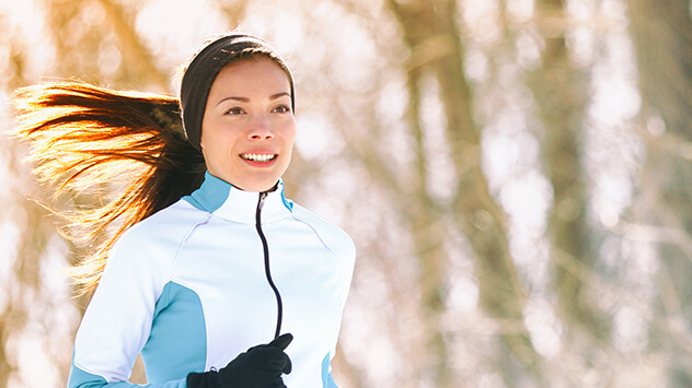 Eine Frau joggt durch den winterlichen Wald