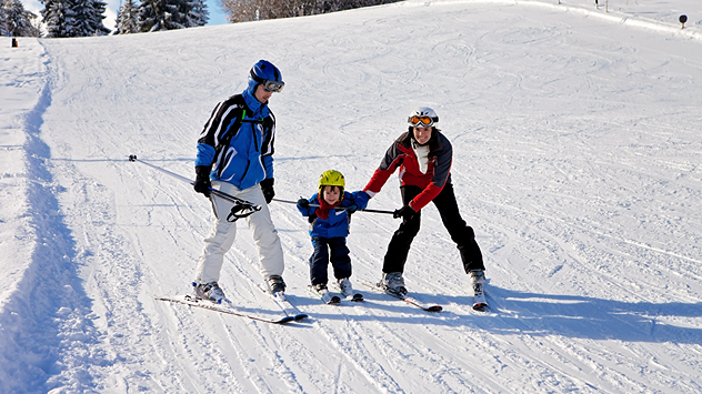 Eine Familien mit kleinem Kind auf einer Skipiste. 
