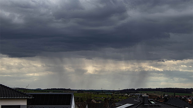 Dunkle Schauerwolken mit Regenstreifen über einer Stadt