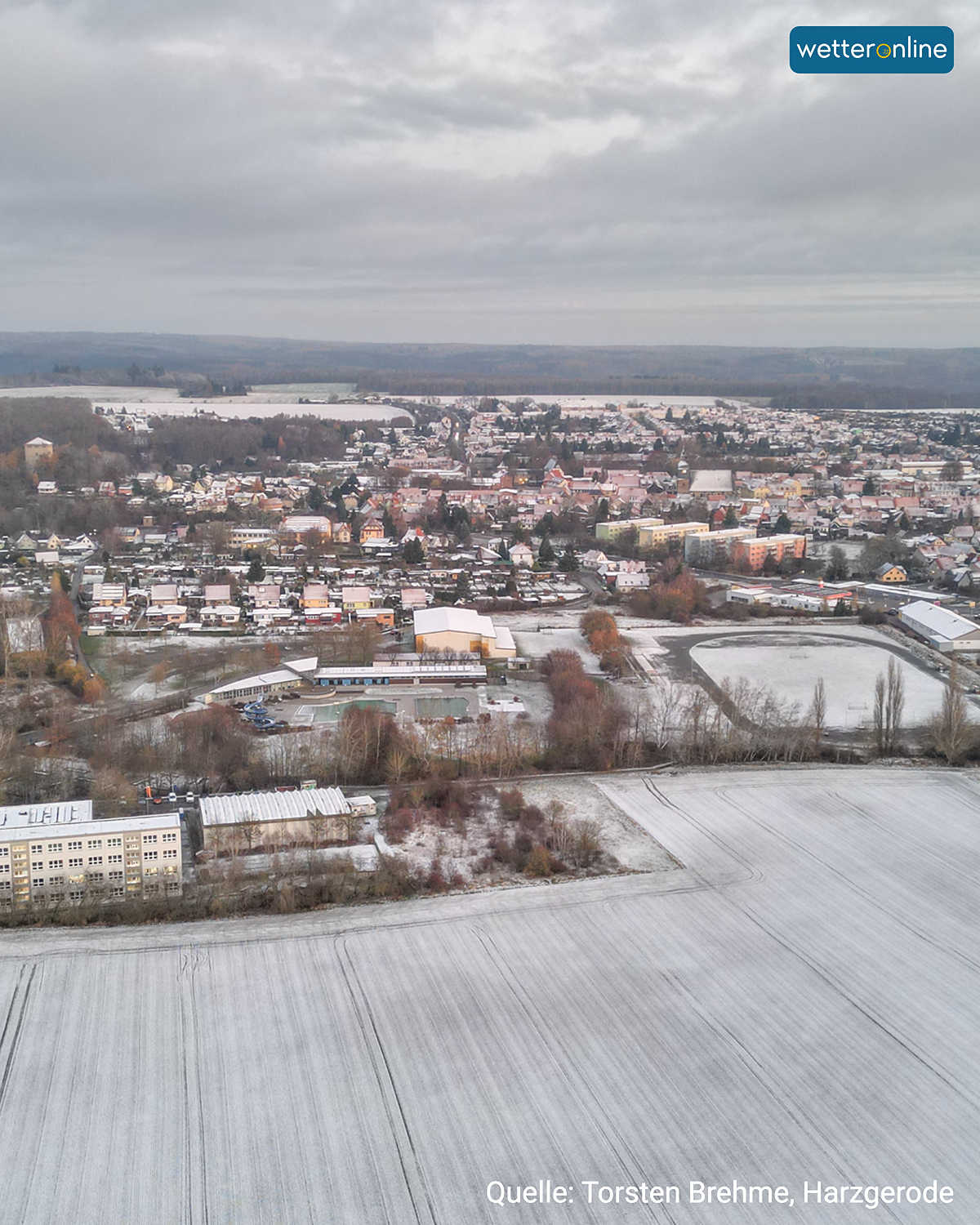 Luftaufnahme von Harzgerode mit leicht verschneiten Feldern und Häusern unter grauem Himmel.