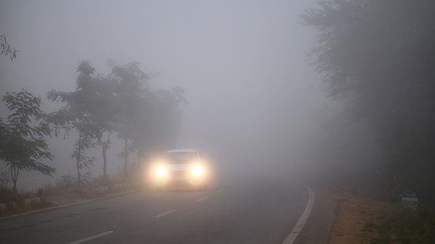 Ein Auto fährt bei Nebel auf der Straße.