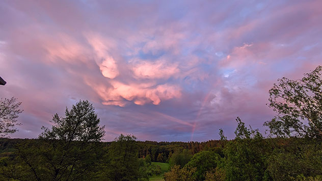 Ein Regenbogen taucht hinter einem Schauer auf. 
