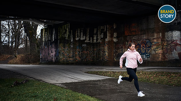 Junge Frau joggt bei Regenwetter.