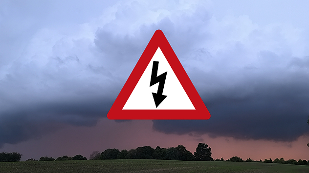 Dunkle Gewitterwolken über einer Landschaft mit einem Warnsymbol für Gewitter.