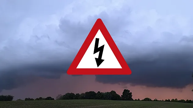 Dunkle Gewitterwolken über einer Landschaft mit einem Warnsymbol für Gewitter.