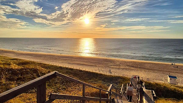 Sonnenuntergang über der Nordsee auf Sylt mit Strand, Dünen und Treppe zum Meer.