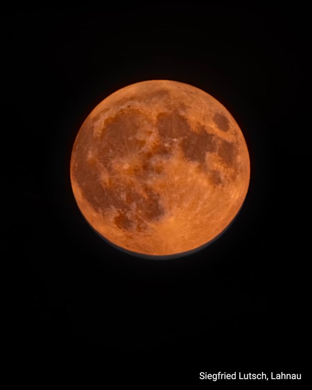 Orangefarbener Erdbeermond mit deutlich sichtbaren Kratern vor schwarzem Nachthimmel.