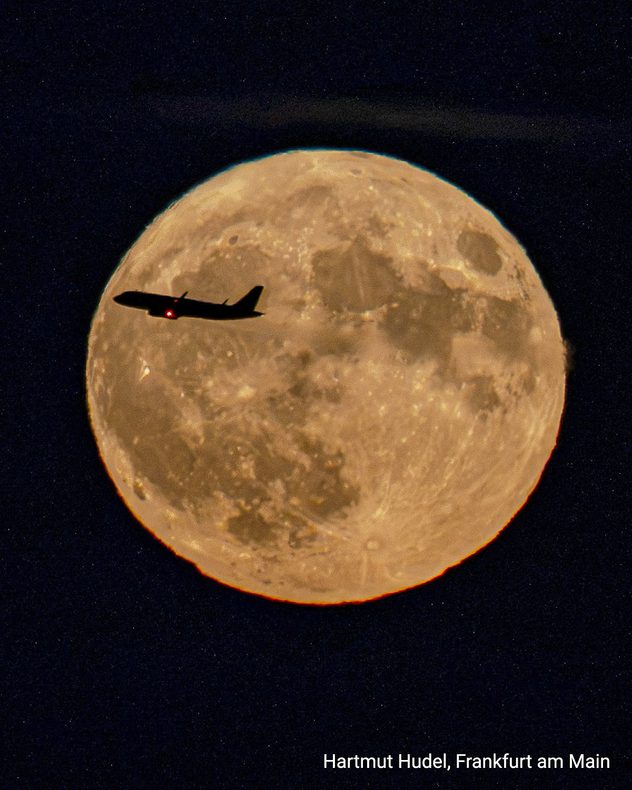 Flugzeug vor einem großen Vollmond am Nachthimmel bei Frankfurt am Main.