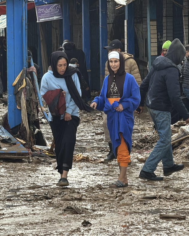 Des gens marchent dans des rues boueuses après de fortes pluies, à côté d'une carte des précipitations au Maroc.
