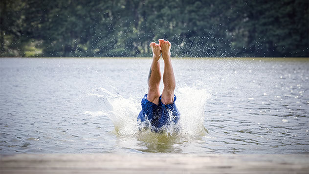 Ein Mann springt kopfüber in einen See
