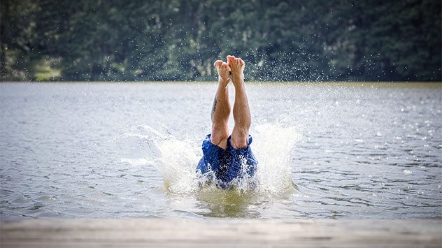 Ein Mann springt kopfüber in einen See
